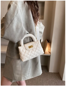Detail of white quilted handbag with golden twist lock and hard top handle