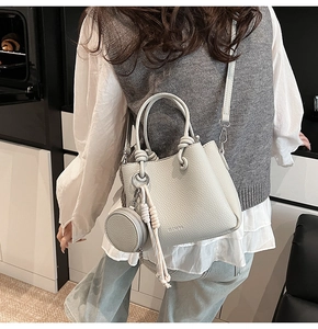 Back view of light grey lychee pattern bucket bag with mini purse charm and shoulder strap