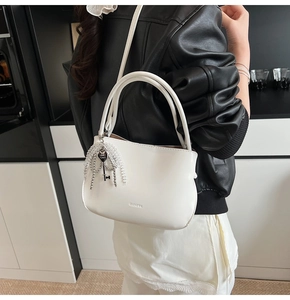 Detail der weißen Leder-Beuteltasche mit silbernem Schlüsselanhänger und Perlen