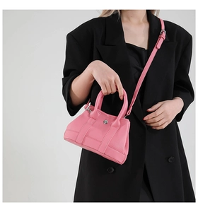 Detail view of pink lychee leather bucket bag styled with a black oversized blazer
