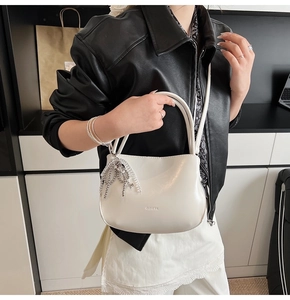 Detail of white PU bucket bag with silver beaded tassel and metal key charm accessory