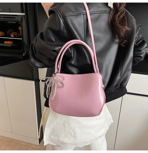 Close-up of pink shiny PU bucket bag with CLEARUK logo and pearl bow charm detail