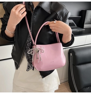 Détail du sac seau rose avec nœud perlé et breloque clé porté par un mannequin en veste