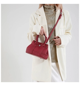 Detail shot of wine red litchi texture leather tote with metallic snap and thin strap