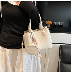 Detail of cream lychee leather bucket bag featuring knot handle and mini coin purse