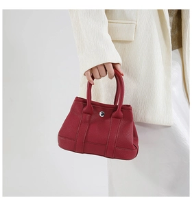Macro shot of red lychee textured leather handbag with metallic buckle and vertical strap
