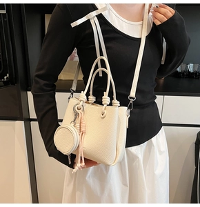 Close-up of white pebble leather bucket bag featuring a round coin purse and woven rope