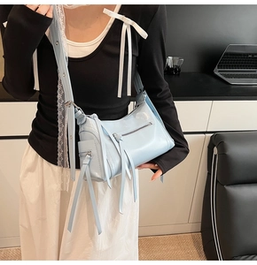Detalle de bandolera azul claro con flecos largos de moda y correa metálica ajustable