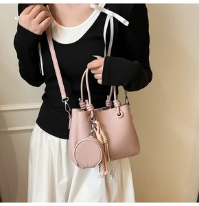 Close-up of pink litchi grain leather bucket bag with unique knotted handle and brand logo