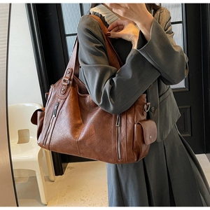Detail view of large brown retro tote bag featuring side pockets and bronze hardware