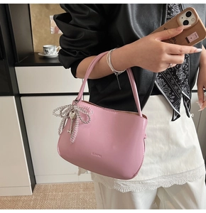 Detailansicht der rosa Ledertasche mit Perlen-Schleife und eingeprägtem Markenlogo