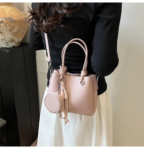 Detail of pink bucket bag with pebbled leather texture and mini coin purse pendant