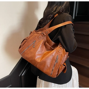 Detail of caramel brown slouchy hobo bag featuring multiple zippers and side pocket