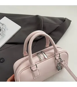 Detail of light pink mini Boston bag featuring silver hardware lock and dual zippers
