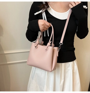 Close-up of pink litchi grain leather bucket bag with elegant metal ring and knot details