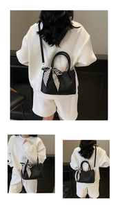 Détail du sac seau noir en cuir grainé avec foulard en soie pied-de-poule et bandoulière