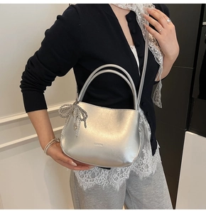 Close-up of silver PU bucket bag with beaded bow charm and debossed logo detail