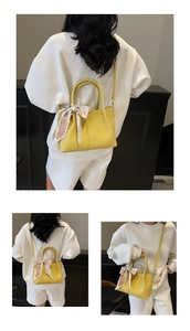 Détail du sac seau jaune avec texture litchi et poignée décorée d'un foulard en soie