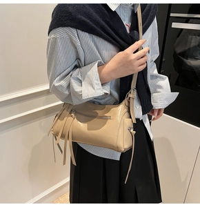 Detalle de bolso bandolera beige en cuero de alta calidad con borlas largas decorativas