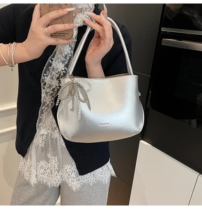 Detail of silver metallic bucket bag with beaded bow charm and metal key pendant