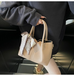 Détail du sac seau beige avec texture litchi et foulard en soie décorant la poignée