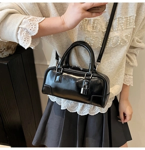 Detail of glossy black mini Boston bag with silver padlock and smooth leather texture