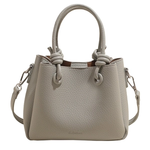 Light gray pebbled leather bucket bag with top knot handle and slim crossbody strap