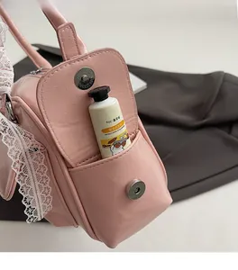 Detail of pink Boston bag side pocket with lace trim showing storage for hand cream