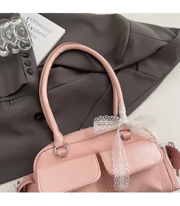 Detail of pink faux leather Boston bag featuring white lace bows and double front pockets