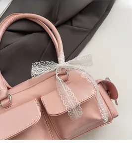 Detail of light pink leather Boston bag featuring cargo pockets and white lace bow decoration