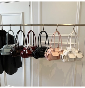 Detailed display of six colorful glossy patent leather Boston bags hanging on a rack