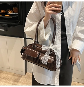 Close-up of brown faux leather Boston bag with white lace bows and double handles