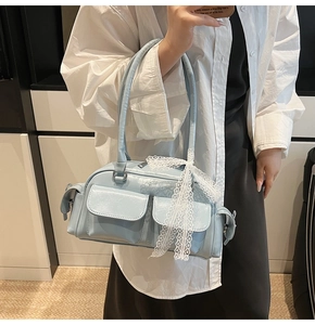 Detail of light blue Boston bag featuring multiple pockets and a white lace bow ornament