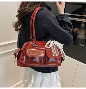 Detail of red patent leather Boston bag with double front pockets and lace bow accessory