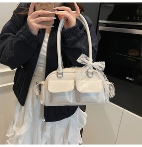 Close-up of beige patent leather Boston bag featuring cargo pockets and lace bow detail
