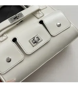 Detail of a creamy white handbag featuring silver metal twist locks and stud accents