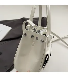 Detail of white minimalist handbag showing silver metal snaps and matte synthetic leather