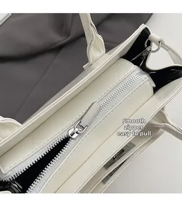 Detail shot of a smooth silver metal zipper on a white minimalist faux leather handbag