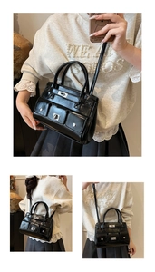Detail view of black patent leather multi-pocket tote bag with silver metal twist lock