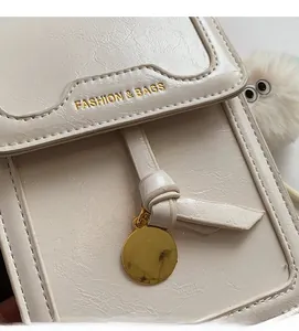 Close-up of cream faux leather crossbody bag with lychee texture and gold branding