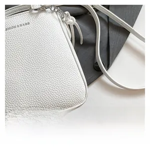 Close-up of premium white lychee grain leather texture and silver hardware on bucket bag