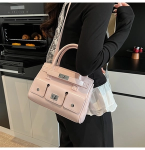 Detail of pink patent leather handbag with dual front pockets and metal lock in a kitchen setting