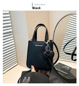 Close-up of black lychee grain leather bucket bag with heart charm and white text