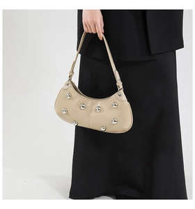 Détail du sac hobo avec clous métalliques argentés et finition crème brillante