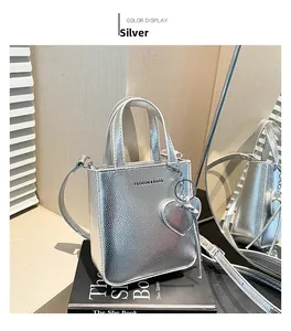 Detail of silver bucket bag with litchi grain texture and heart charm on mirror surface