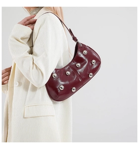 Détail du sac demi-lune bordeaux avec rivets argentés et texture cuir poli