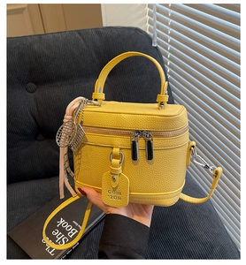 Détail du sac boîte en cuir jaune avec boucles argentées et breloque de tennis