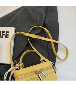 Détail du sac à main en cuir jaune avec une bandoulière lisse et réglable en cuir