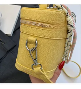 Détail du mini sac jaune en cuir grainé avec fermoir argenté et poignée tressée