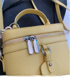 Gros plan du sac en cuir jaune avec doubles fermetures éclair argentées lisses